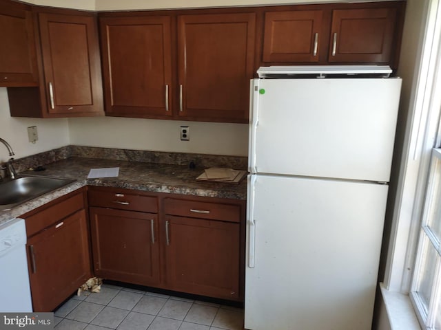 kitchen featuring dark stone countertops, sink, white appliances, and light tile patterned floors