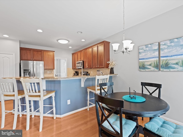 kitchen with decorative light fixtures, light hardwood / wood-style flooring, decorative backsplash, and appliances with stainless steel finishes