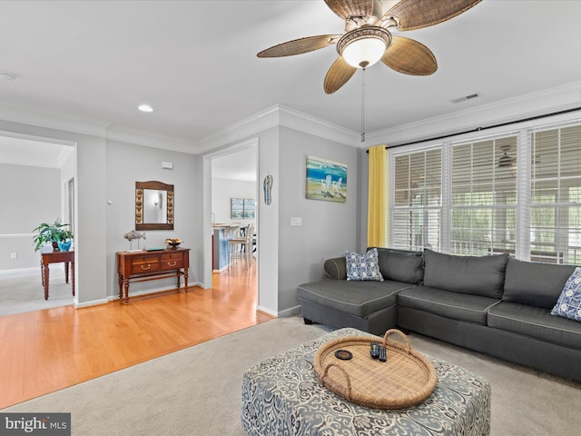 carpeted living room featuring ornamental molding and ceiling fan