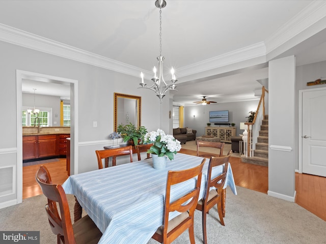 dining area with crown molding, sink, ceiling fan with notable chandelier, and light hardwood / wood-style floors