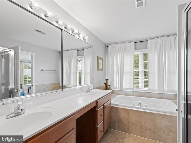 bathroom with tile patterned flooring, tiled tub, and plenty of natural light