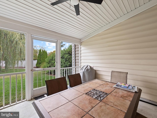 unfurnished sunroom with ceiling fan, vaulted ceiling, and a healthy amount of sunlight