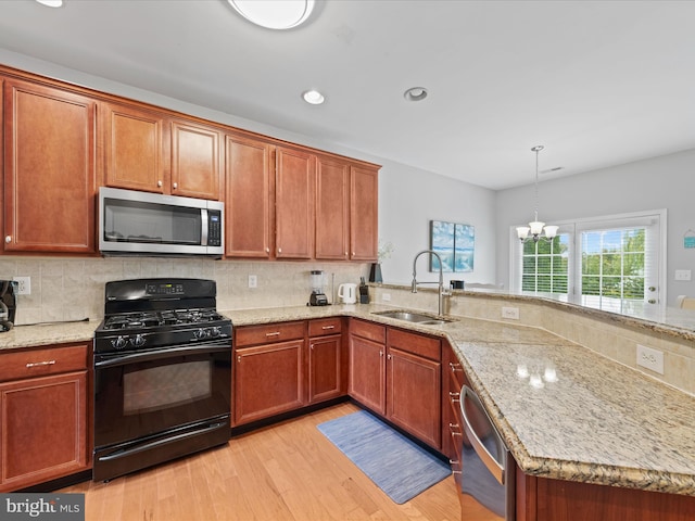 kitchen featuring sink, light hardwood / wood-style flooring, hanging light fixtures, backsplash, and black range with gas stovetop