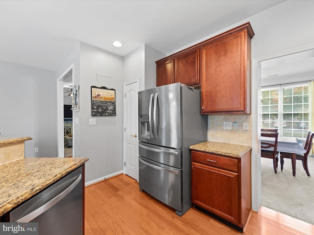 kitchen featuring light stone countertops, backsplash, light hardwood / wood-style flooring, and stainless steel appliances