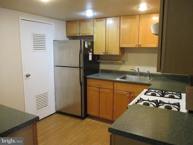 kitchen with sink, white gas range oven, stainless steel refrigerator, and light wood-type flooring