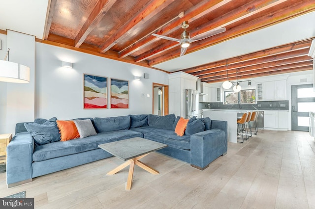 living room with beamed ceiling, ceiling fan, and light wood-type flooring