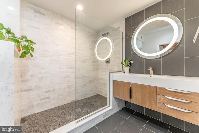 bathroom featuring vanity, tiled shower, tile walls, and tile patterned floors