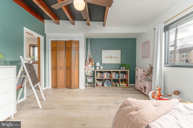 bedroom with ceiling fan, beam ceiling, a closet, and light wood-type flooring