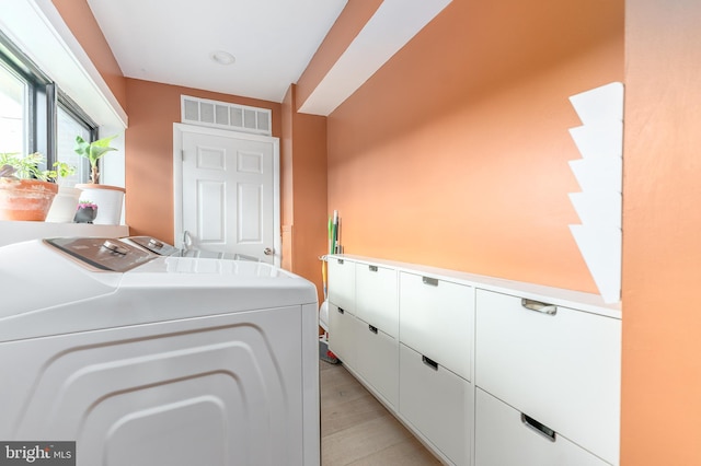 laundry room featuring cabinets, light hardwood / wood-style floors, and independent washer and dryer