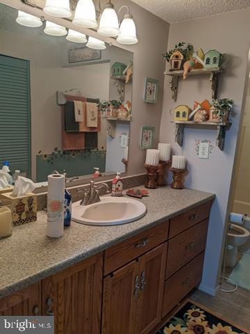 bathroom with vanity, toilet, and a textured ceiling