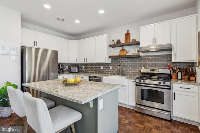 kitchen with sink, white cabinetry, stainless steel appliances, a center island, and dark parquet floors