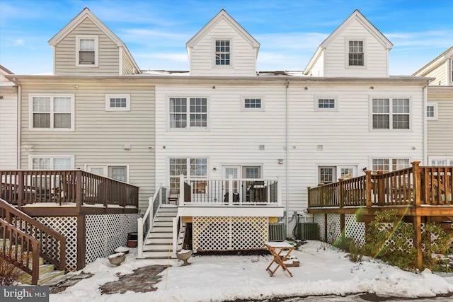 snow covered property with central AC and a deck