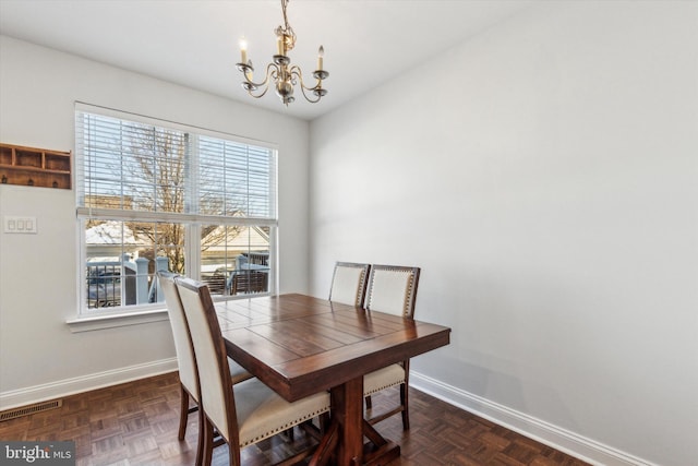 dining space featuring an inviting chandelier, plenty of natural light, and dark parquet floors