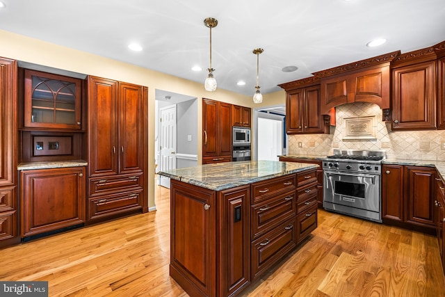 kitchen with pendant lighting, stainless steel appliances, stone countertops, and light hardwood / wood-style flooring