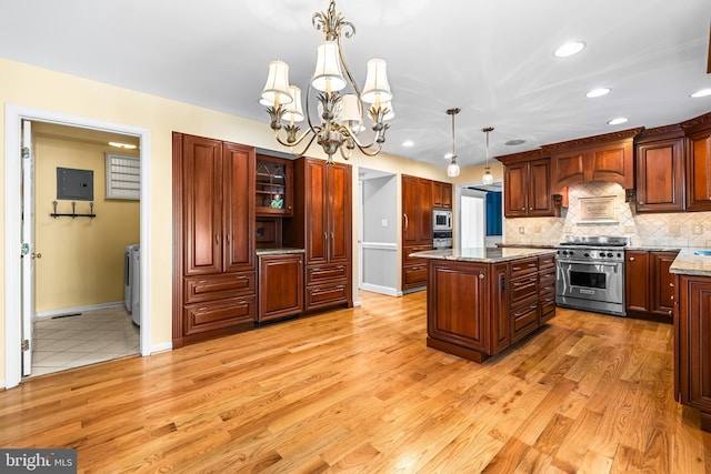 kitchen with decorative light fixtures, a center island, stainless steel appliances, light stone countertops, and backsplash