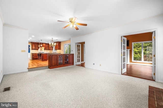 unfurnished living room featuring ornamental molding, light carpet, and a wealth of natural light