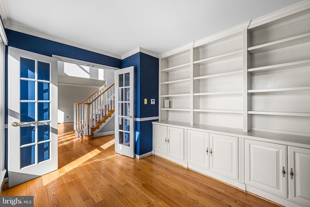 spare room with crown molding, built in shelves, french doors, and light wood-type flooring