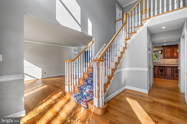 stairs featuring ornamental molding, a towering ceiling, and hardwood / wood-style floors