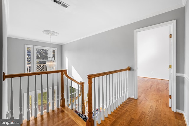 hall featuring an inviting chandelier, crown molding, a wealth of natural light, and light wood-type flooring