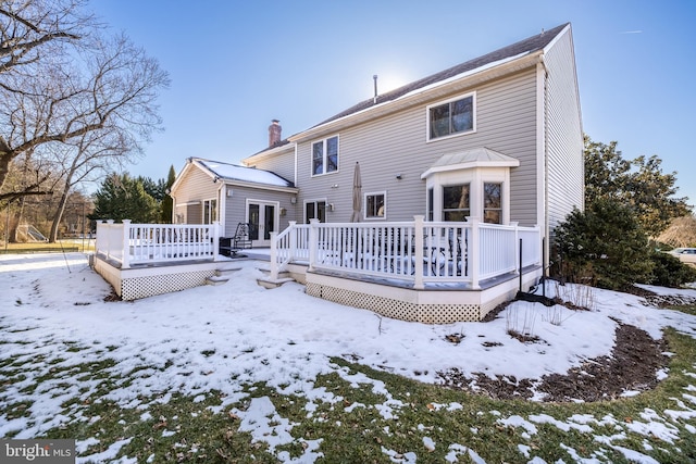 snow covered back of property featuring a deck