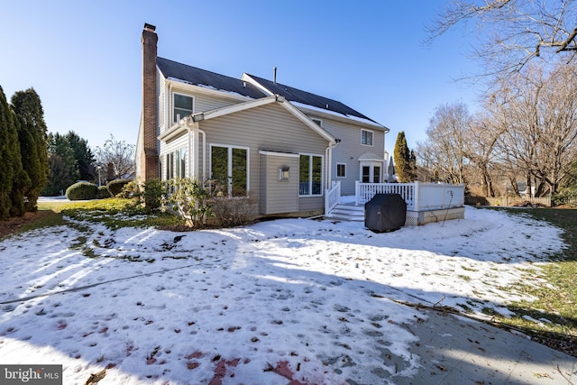 snow covered rear of property with a wooden deck