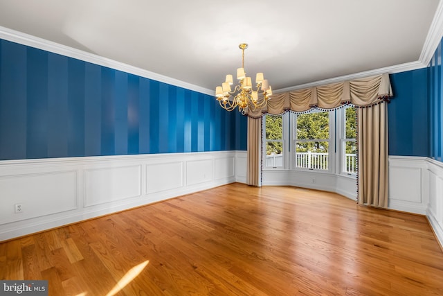 unfurnished room with a notable chandelier, light hardwood / wood-style flooring, and ornamental molding