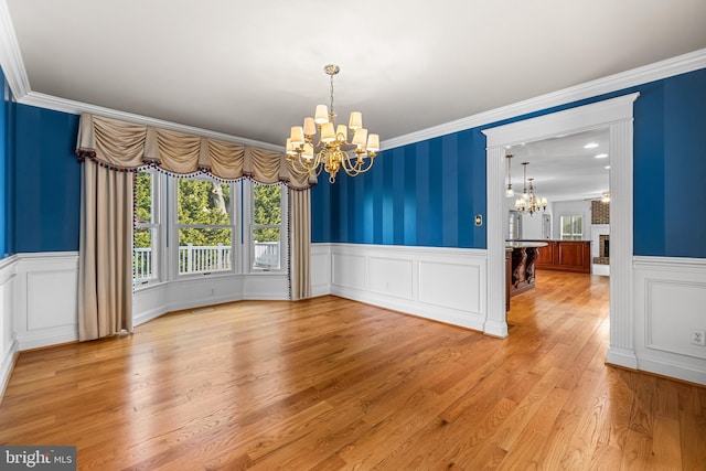 unfurnished dining area featuring crown molding, light hardwood / wood-style floors, and a chandelier