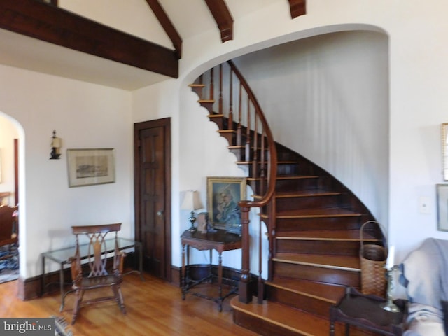 stairway featuring hardwood / wood-style flooring and vaulted ceiling with beams