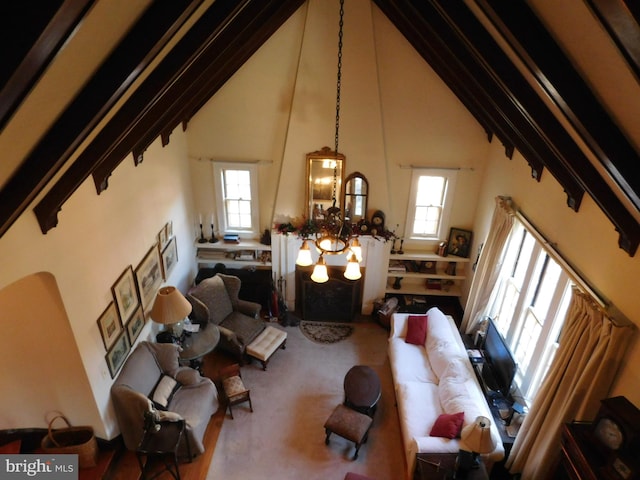 living room featuring carpet floors, a towering ceiling, and an inviting chandelier