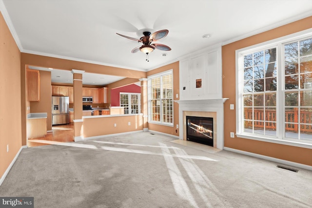 unfurnished living room featuring light colored carpet, ornamental molding, and ceiling fan