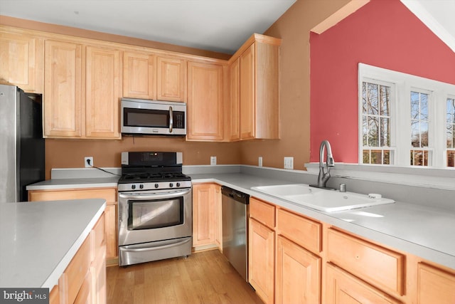 kitchen featuring stainless steel appliances, sink, light brown cabinetry, and light hardwood / wood-style floors