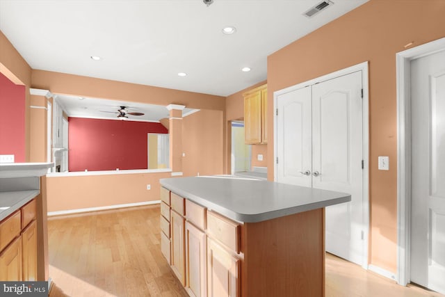 kitchen with a kitchen island, light brown cabinets, ceiling fan, and light hardwood / wood-style flooring