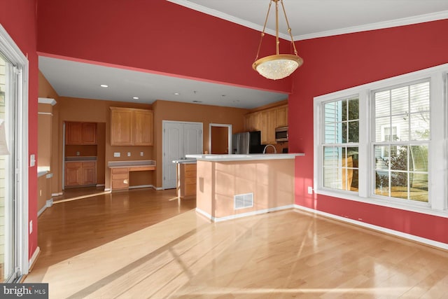 kitchen featuring hanging light fixtures, ornamental molding, light hardwood / wood-style flooring, and kitchen peninsula