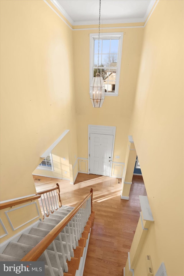 foyer entrance featuring an inviting chandelier, hardwood / wood-style floors, and crown molding