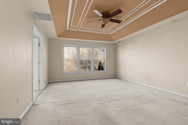 spare room with ceiling fan, light colored carpet, ornamental molding, and a raised ceiling