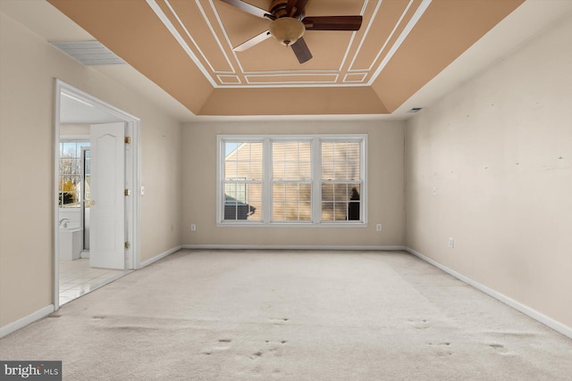 carpeted empty room featuring ceiling fan and a raised ceiling