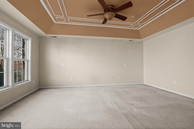 carpeted spare room with ceiling fan and a tray ceiling