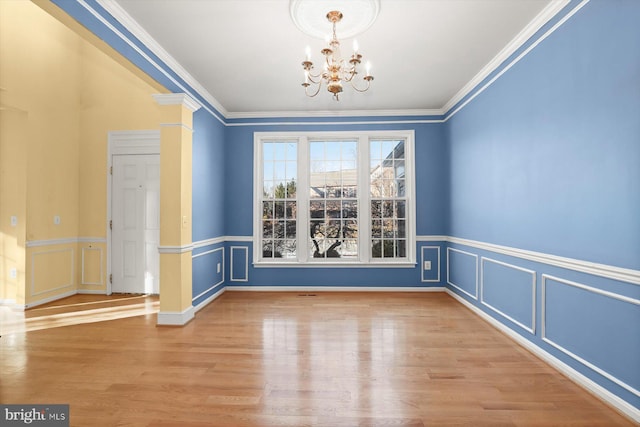 unfurnished dining area with ornamental molding, wood-type flooring, and a chandelier