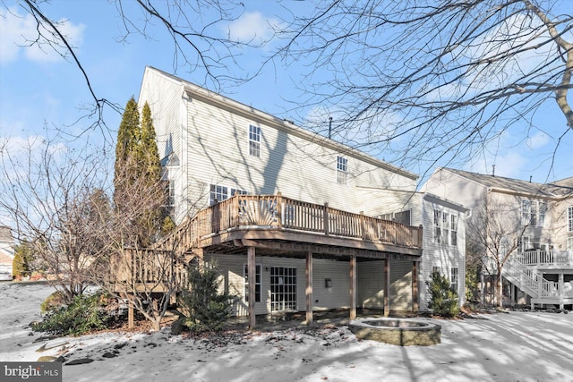 snow covered back of property with a deck