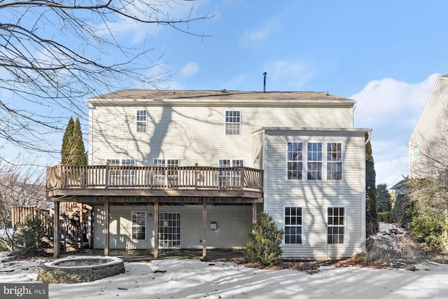 snow covered back of property with a wooden deck