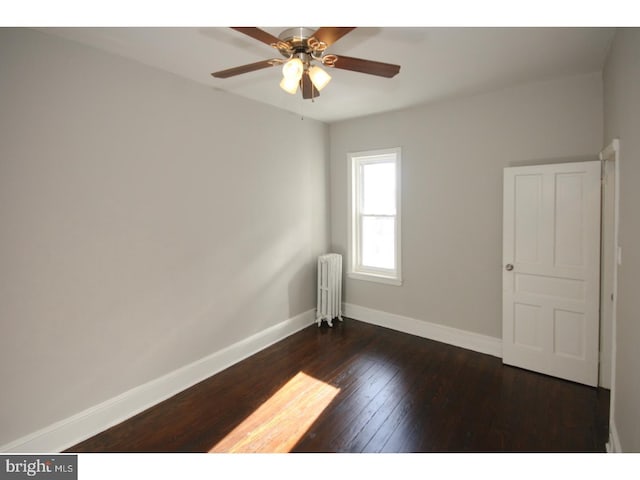 empty room featuring ceiling fan, dark hardwood / wood-style flooring, and radiator