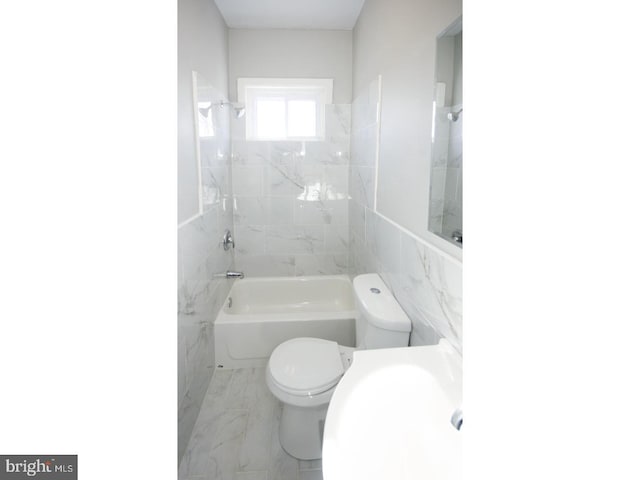 full bathroom featuring toilet, tiled shower / bath combo, sink, and tile walls