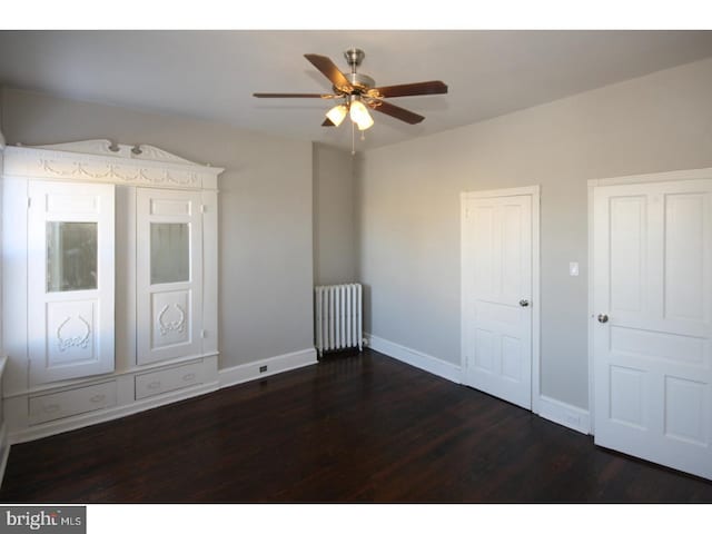 unfurnished bedroom with dark hardwood / wood-style flooring, radiator heating unit, and ceiling fan