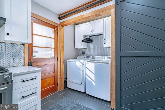 washroom with cabinets, independent washer and dryer, and dark tile patterned floors