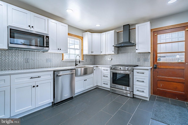 kitchen featuring sink, white cabinetry, stainless steel appliances, decorative backsplash, and wall chimney exhaust hood