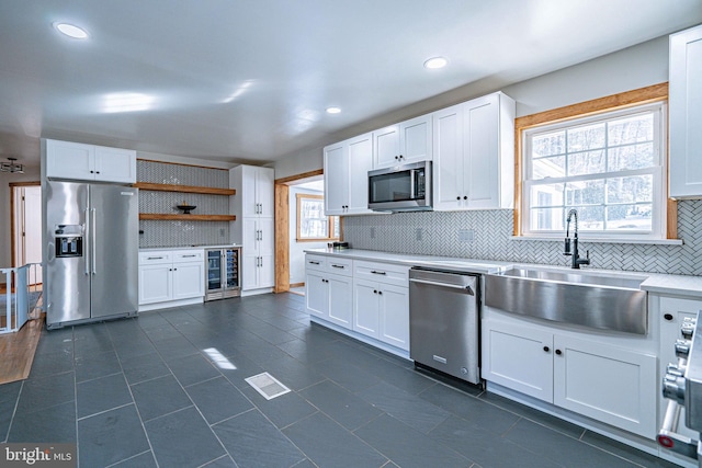 kitchen with white cabinetry, stainless steel appliances, sink, and backsplash