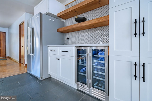 kitchen featuring wine cooler, backsplash, high end refrigerator, and white cabinets