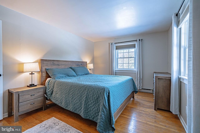 bedroom with dark hardwood / wood-style flooring and a baseboard radiator