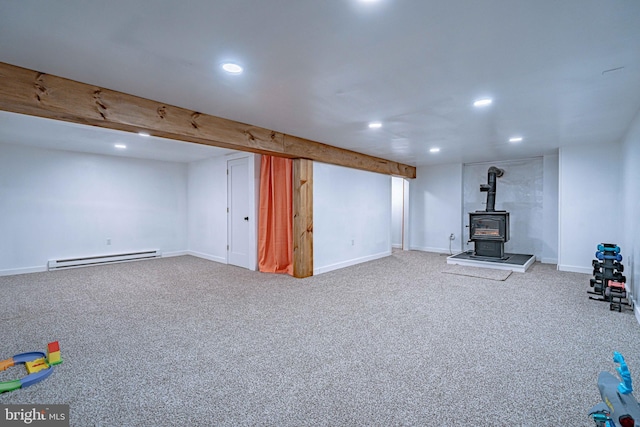 basement featuring carpet flooring, a baseboard radiator, and a wood stove