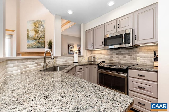 kitchen featuring sink, gray cabinetry, appliances with stainless steel finishes, kitchen peninsula, and light stone countertops